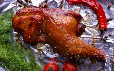 Smoked chicken leg with cherry tomatoes on foil close up