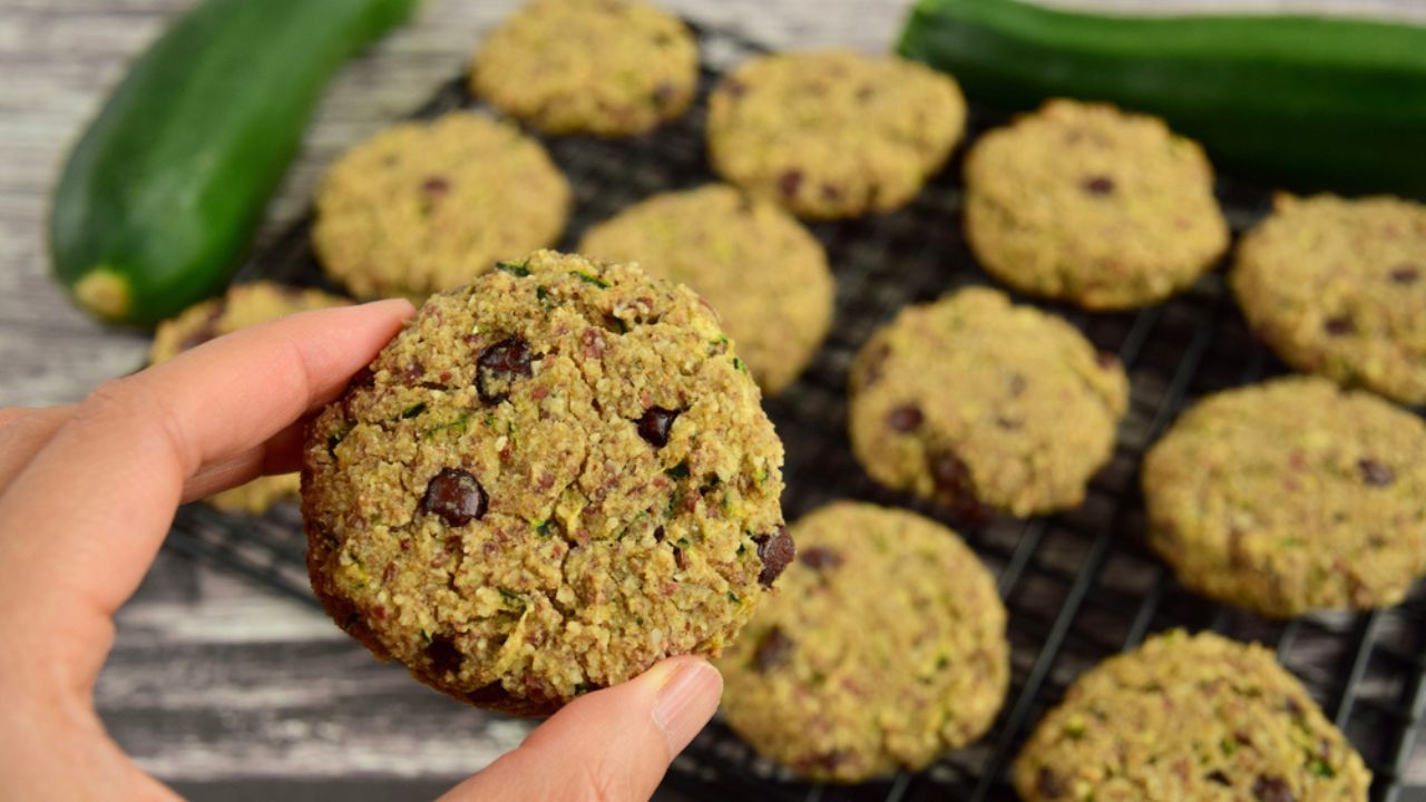 A hand holding zucchini chocolate chip oat cookies on cooling rack. Selective focus