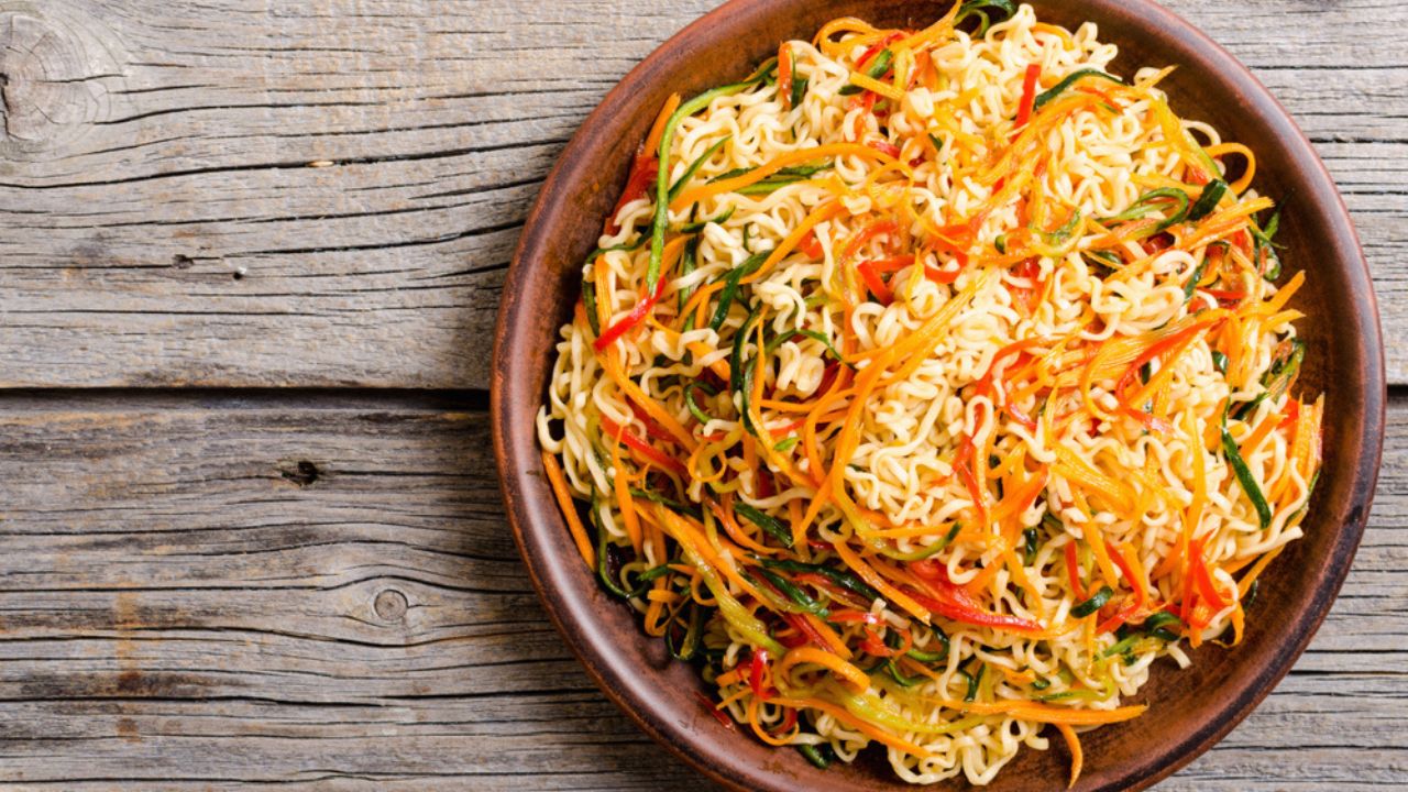 Asian noodles salad in bowl on rustic background