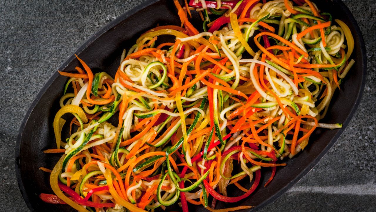 Vegan food, diet. Vegetable noodles, pasta from carrot, zucchini, bell pepper. Ready for baking cooking on a stone table. Copy space top view