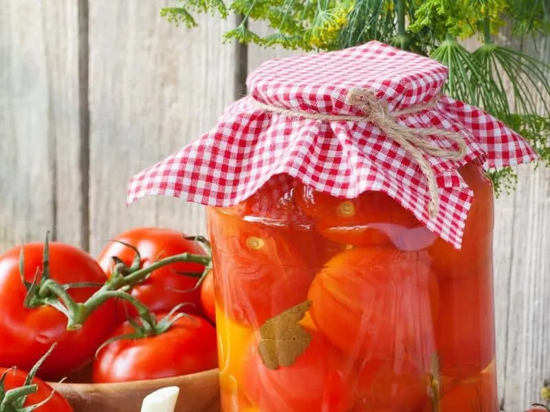 A bowl of tomatoes and a jar of canned tomatoes 