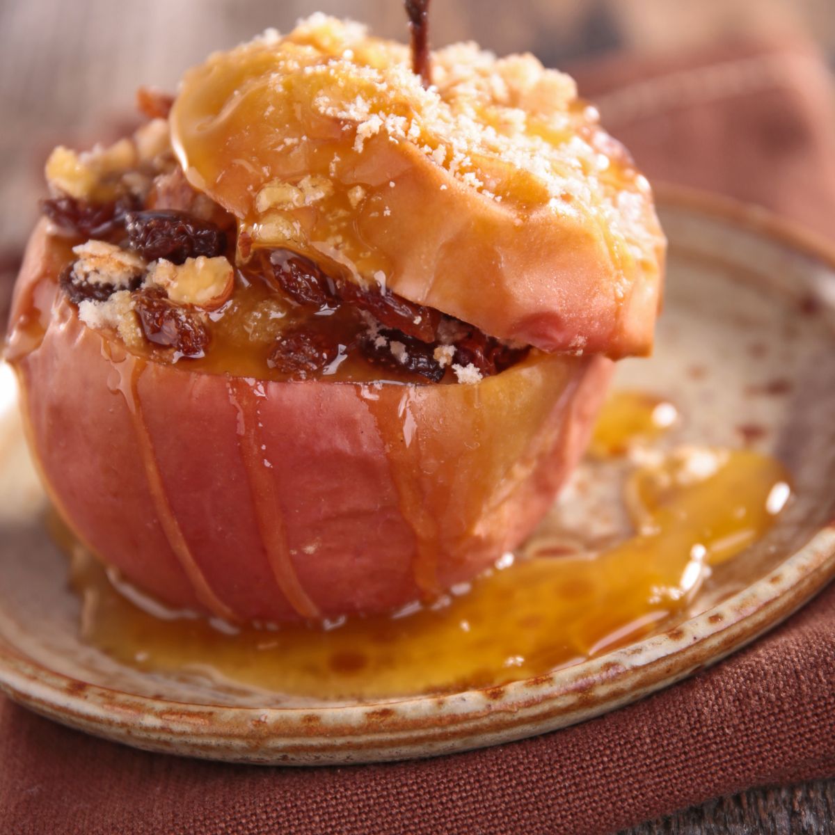 A baked apple topped with raisins, nuts and dripping with gooey sugary syrup. 