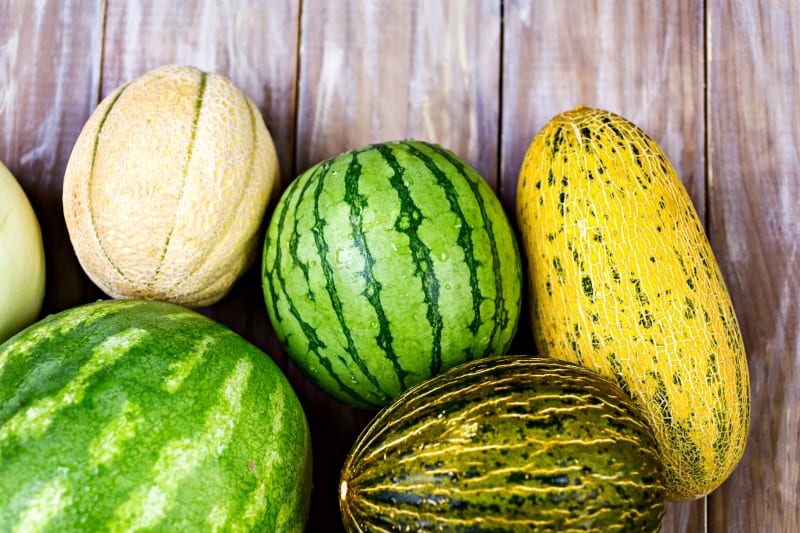 Variery of organic melons on wood board.