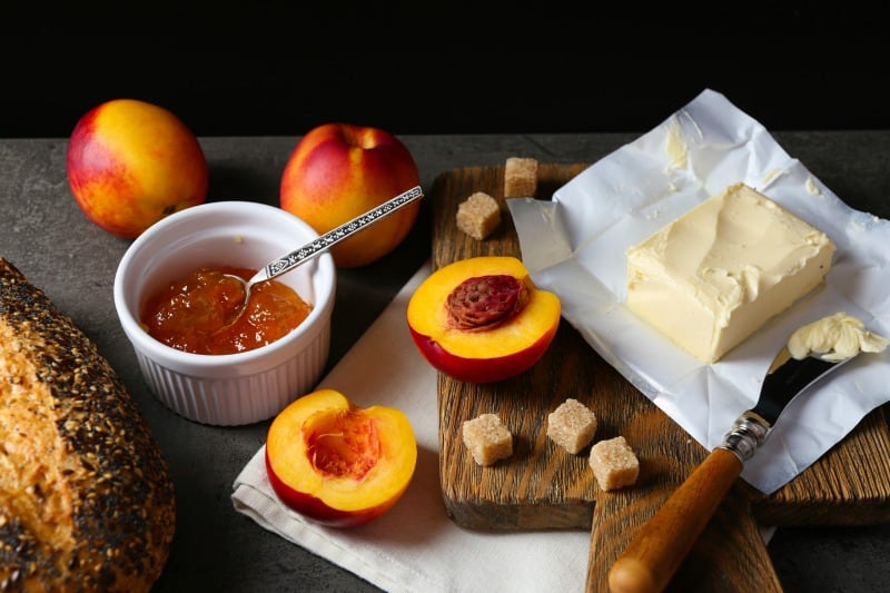 Tasty peach jam in a bowl and ripe peaches