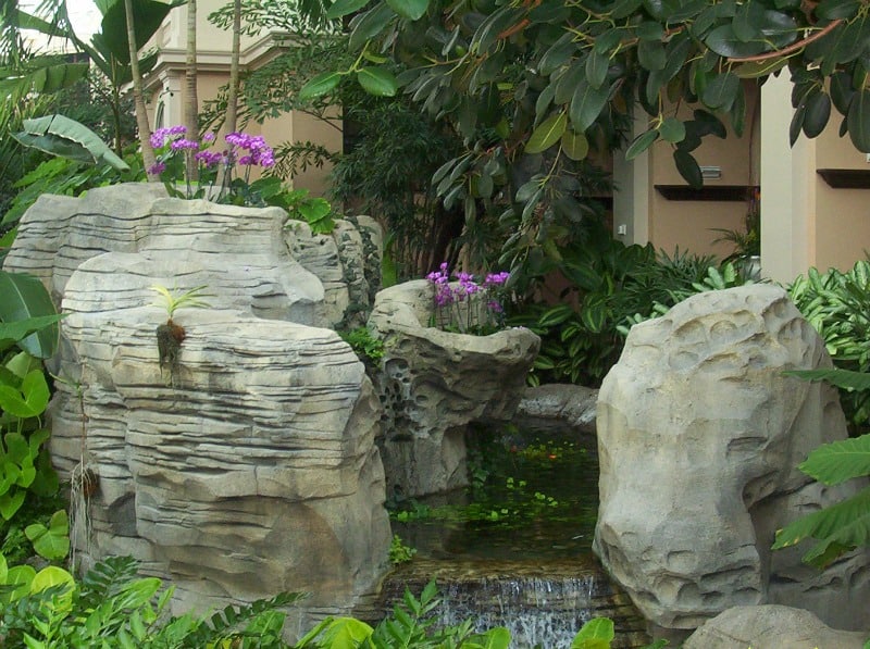 Rockly backyard waterfall with pink flowers