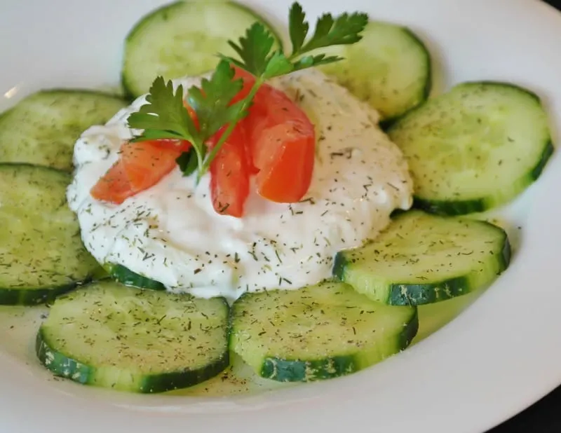 Cucumber salad with dill, cream, and tomato garnish