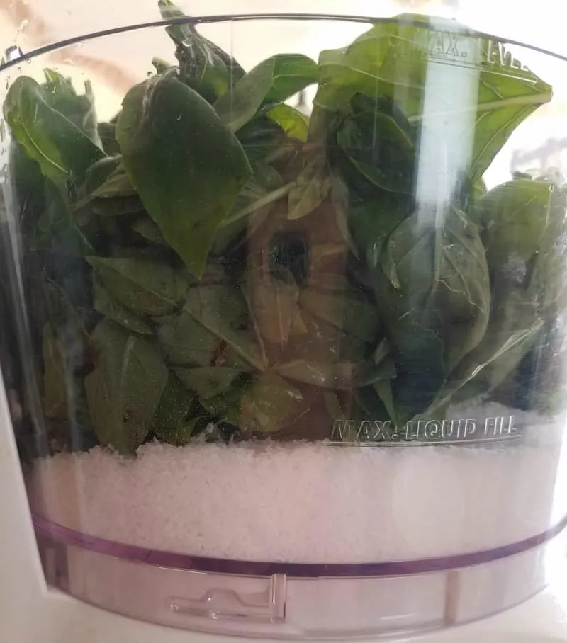 Salt and basil leaves added to the food processor, ready to mix