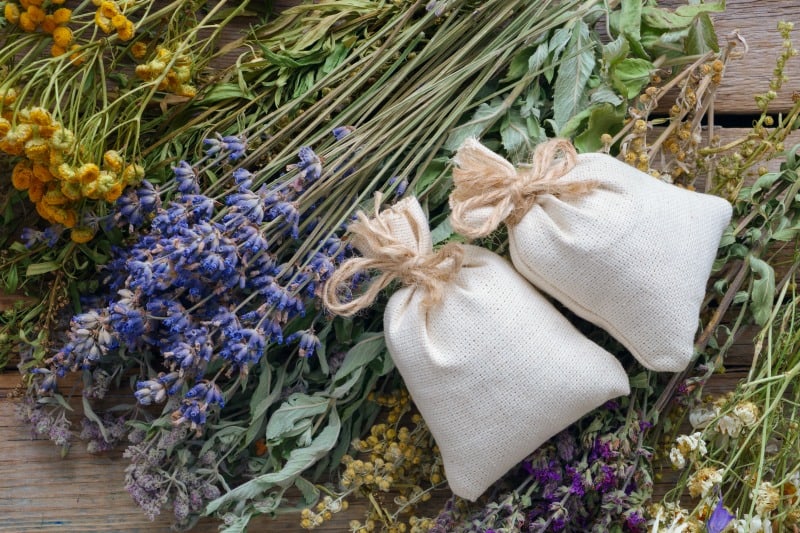 A bunch of healing herbs and sachets on wooden table, ready to make dream herbal pillows