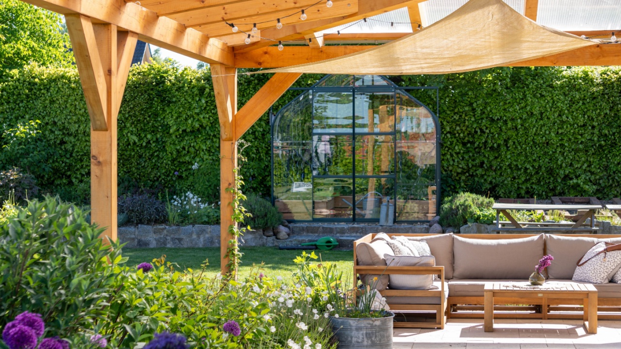 covered terrace with furniture in the garden, glasshouse in the background