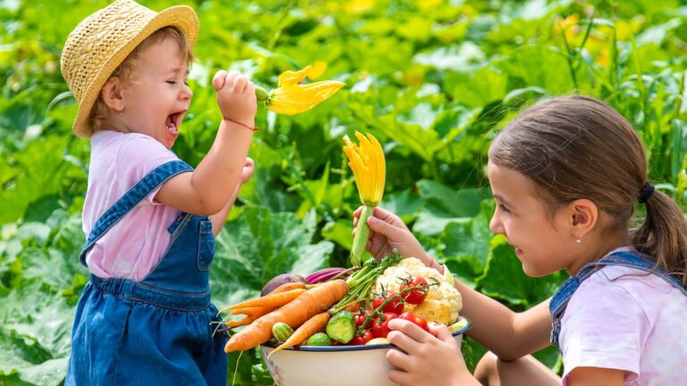Happy kids with a basket of freshly picked vegetables.