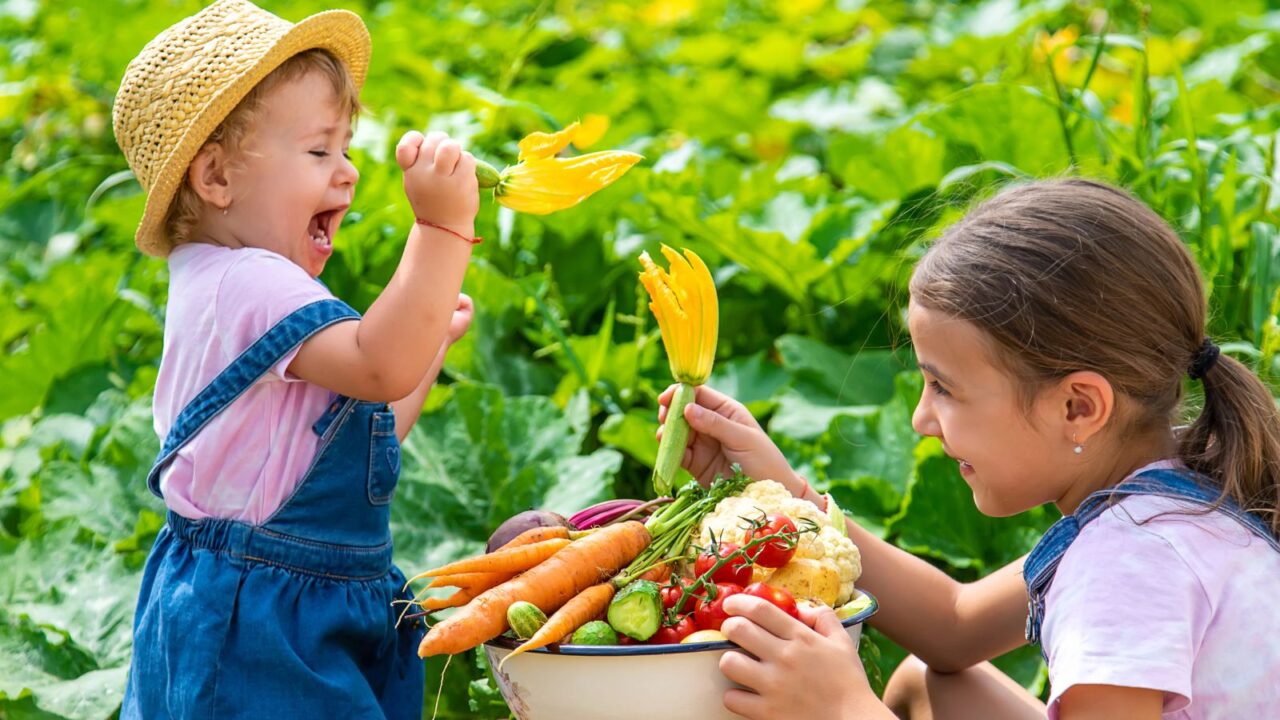 Happy kids with a basket of freshly picked vegetables.