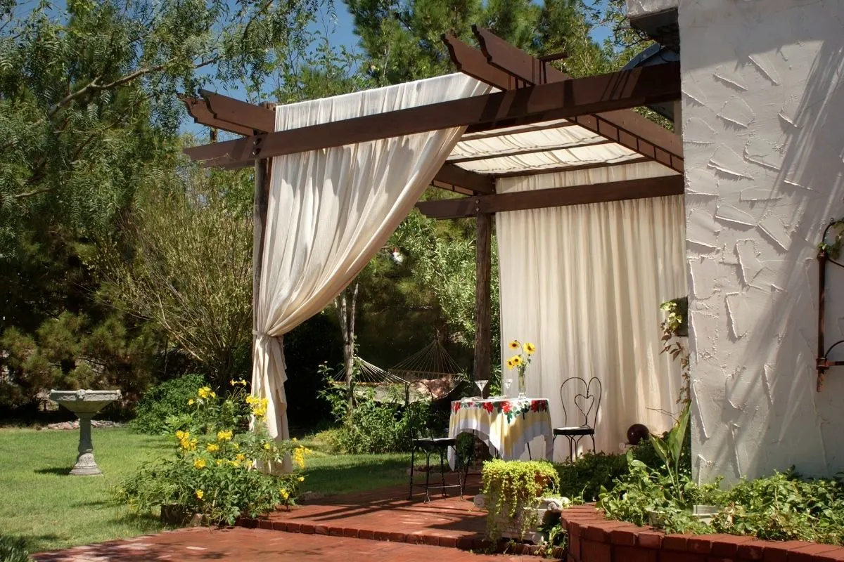 a romantic patio setting with a small table for two and white curtains
