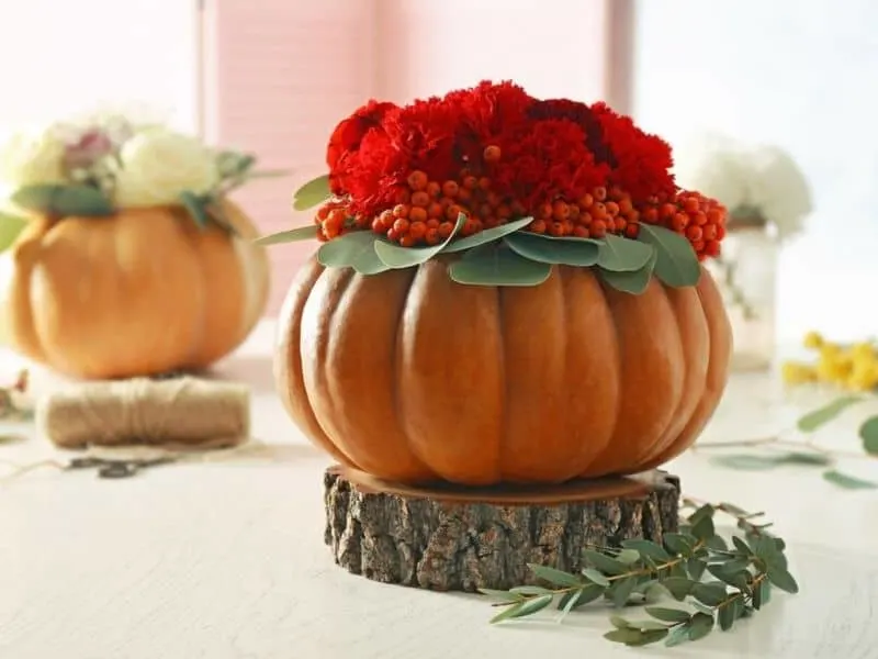 Red flowers and berries in a natural pumpkin bowl