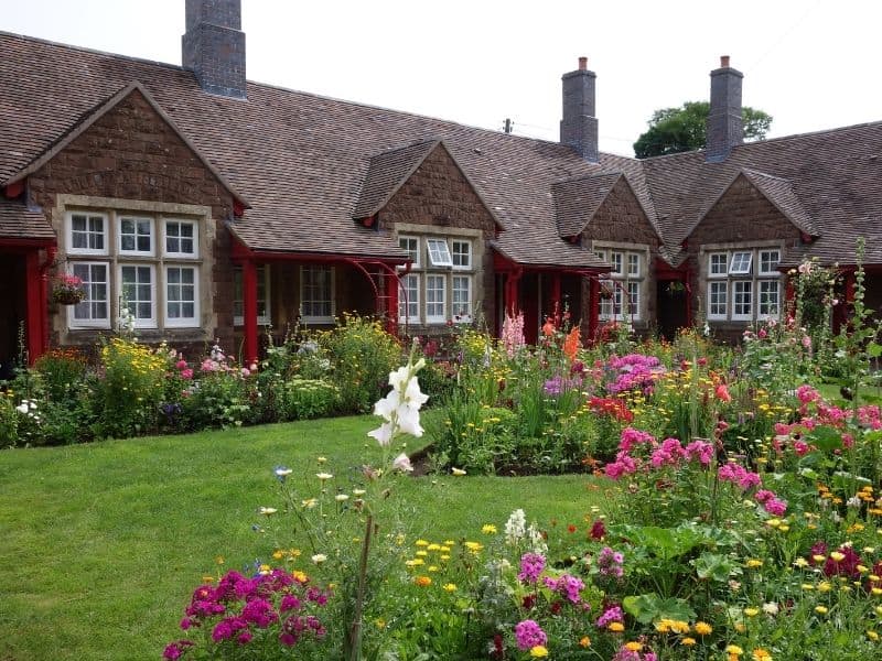 A cottage garden in front of a nice house with slopy terrain