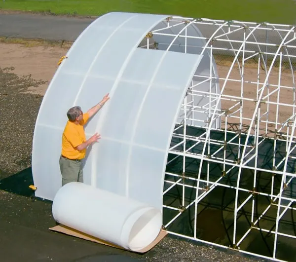 Man adding Solexx covering to his greenhouse frame