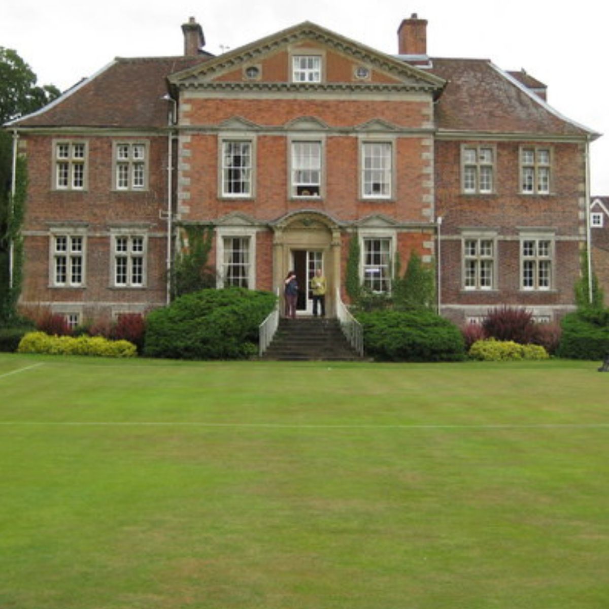 manicured lawn in front of a mansion. 