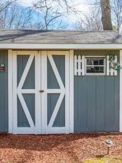 Storage shed painted gray with white accents