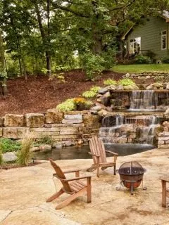 Backyard room with cascading watee, a fire pit and some chairs