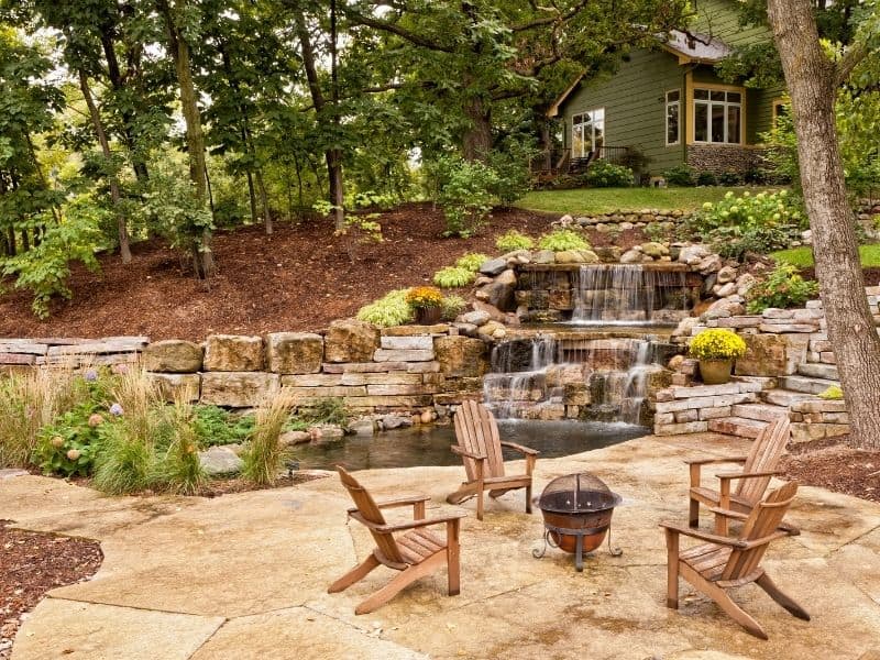 Backyard room with cascading watee, a fire pit and some chairs
