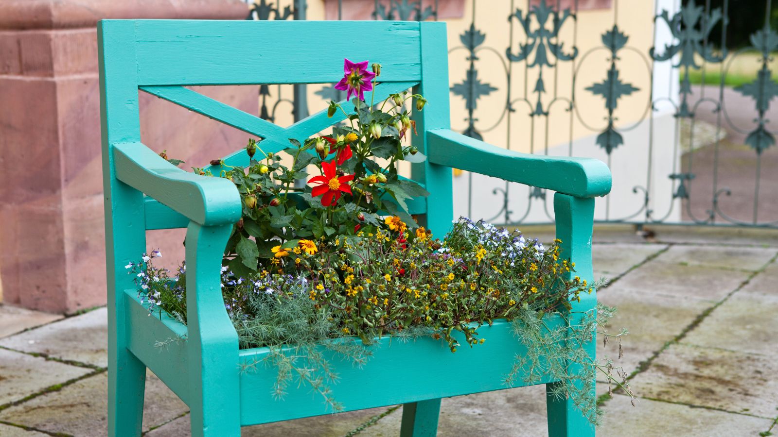 An old chair transformed into a planter and filled with pretty flowers.