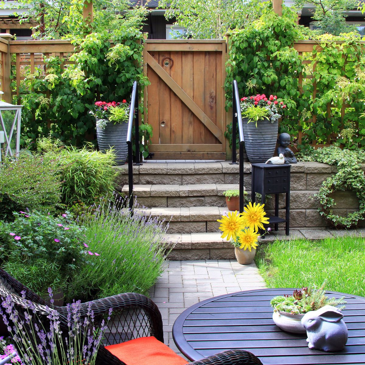 Small backyard garden with flowers, a table, and a chair.