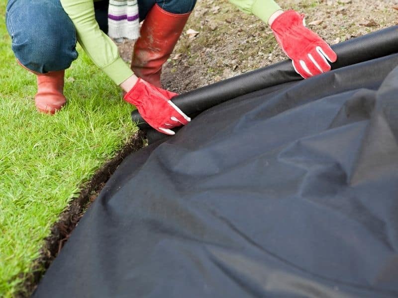 woman laying down weed barrier fabric