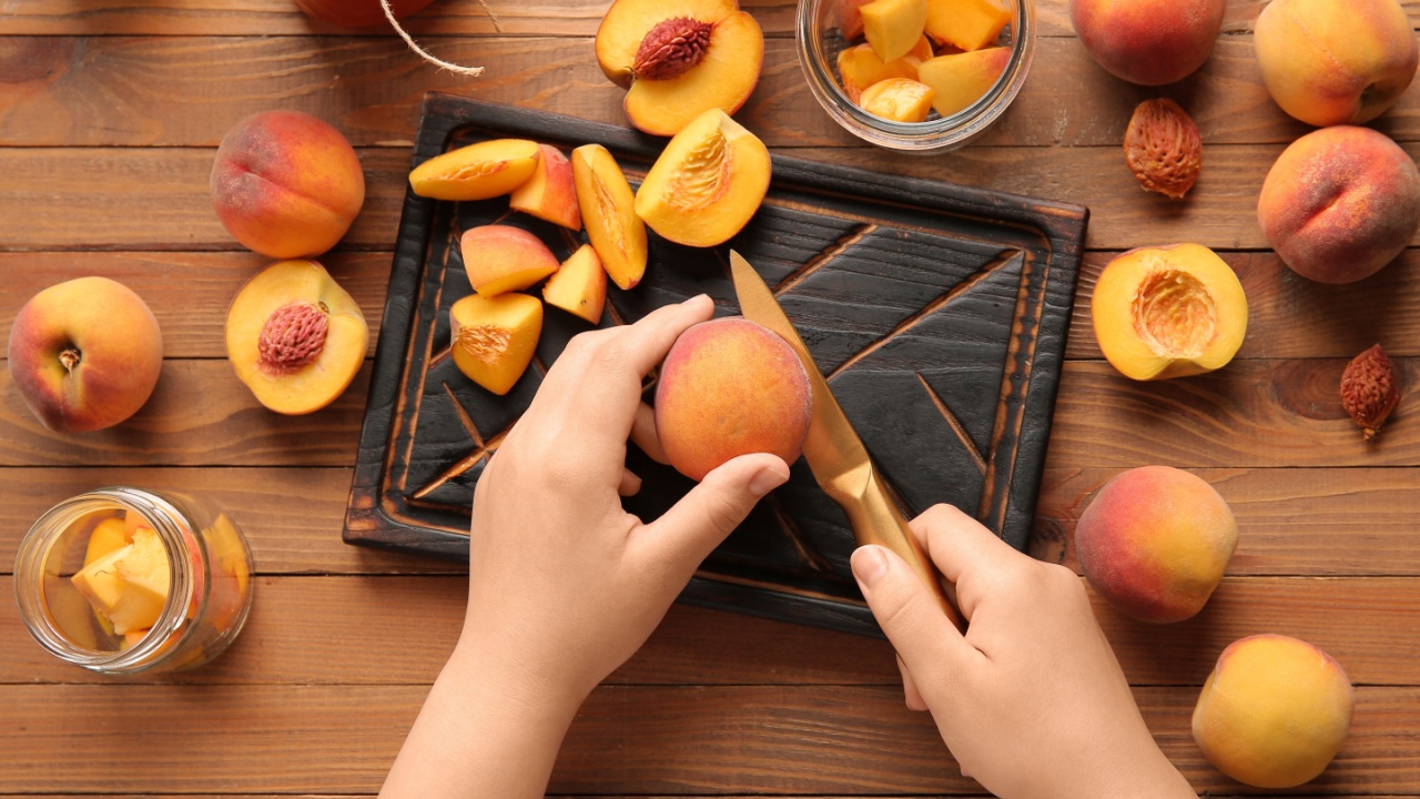 Woman preparing sweet peach jam on wooden background