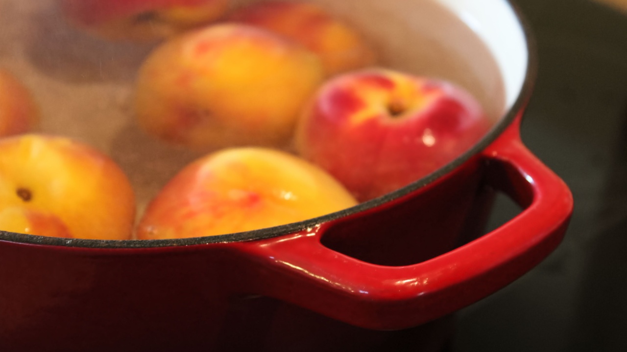Closeup of a red pot handle while blanching peaches.