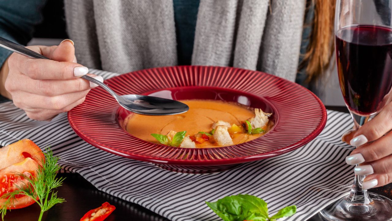 The Concept of Spanish Cuisine. the Girl in the Restaurant Has Gazpacho Soup and Drinks Red Wine. Squeezes Lemon in the Soup.