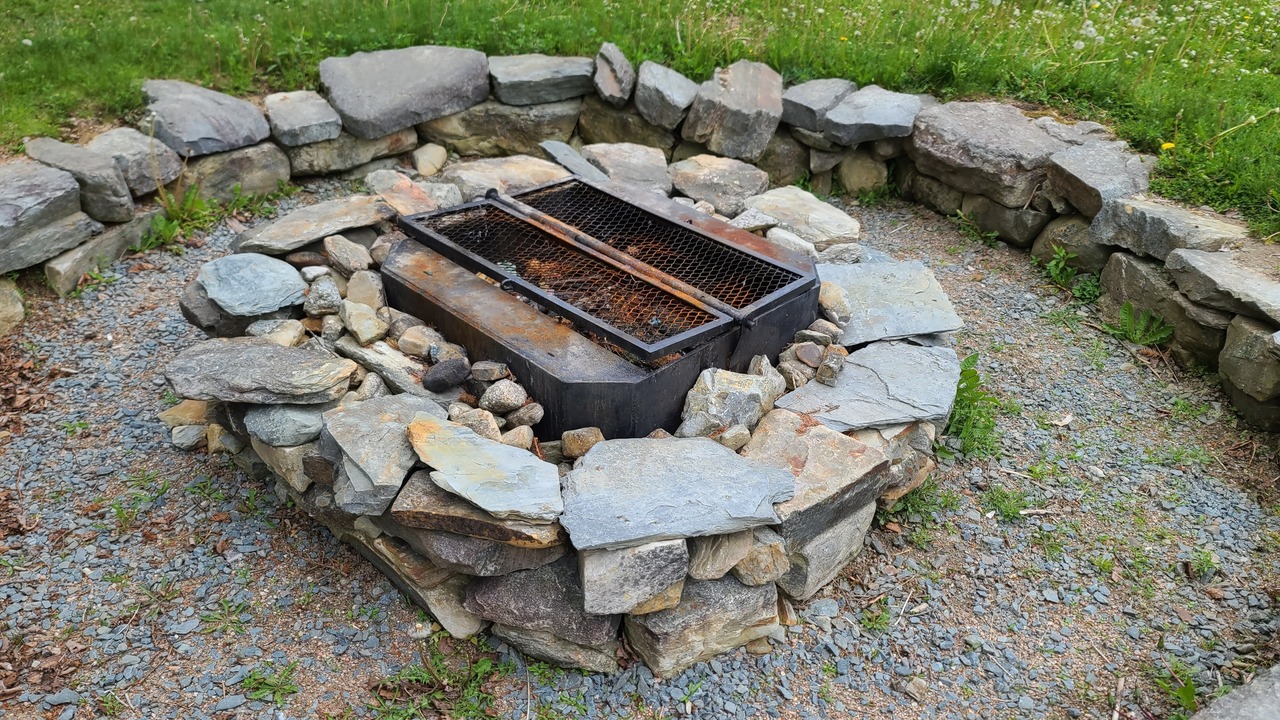 A large dug out firepit with rocks around the side and a rock fire place in the center.