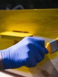 man painting a beehive yellow