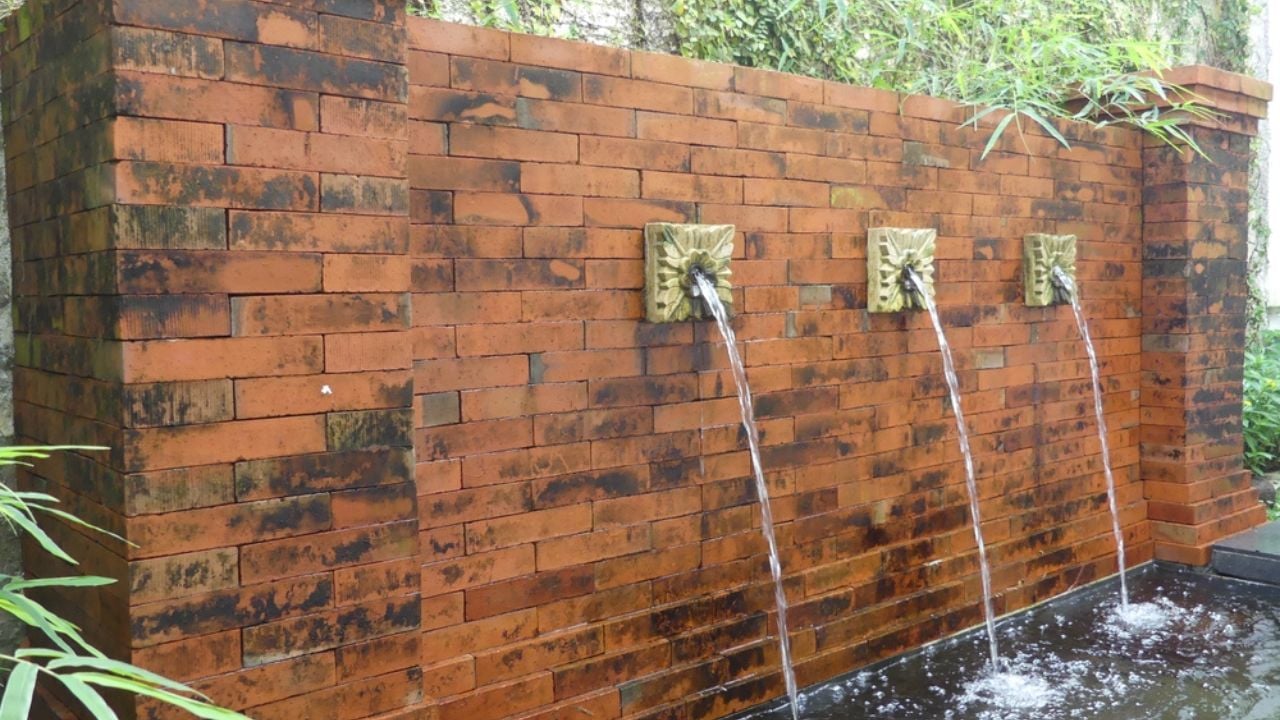 Outdoor decorative water feature with flowing fountains and rustic brick wall