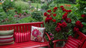Overlooking a colorful backyard garden with casual red furniture and geraniums.in the foreground.