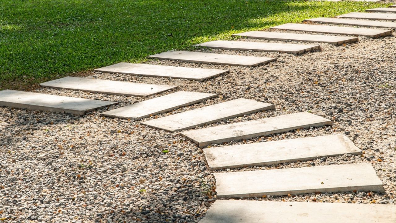 Zigzag arrangement of white concrete pathway alternate with small white rock , pavement in lawn , walk way in the green garden