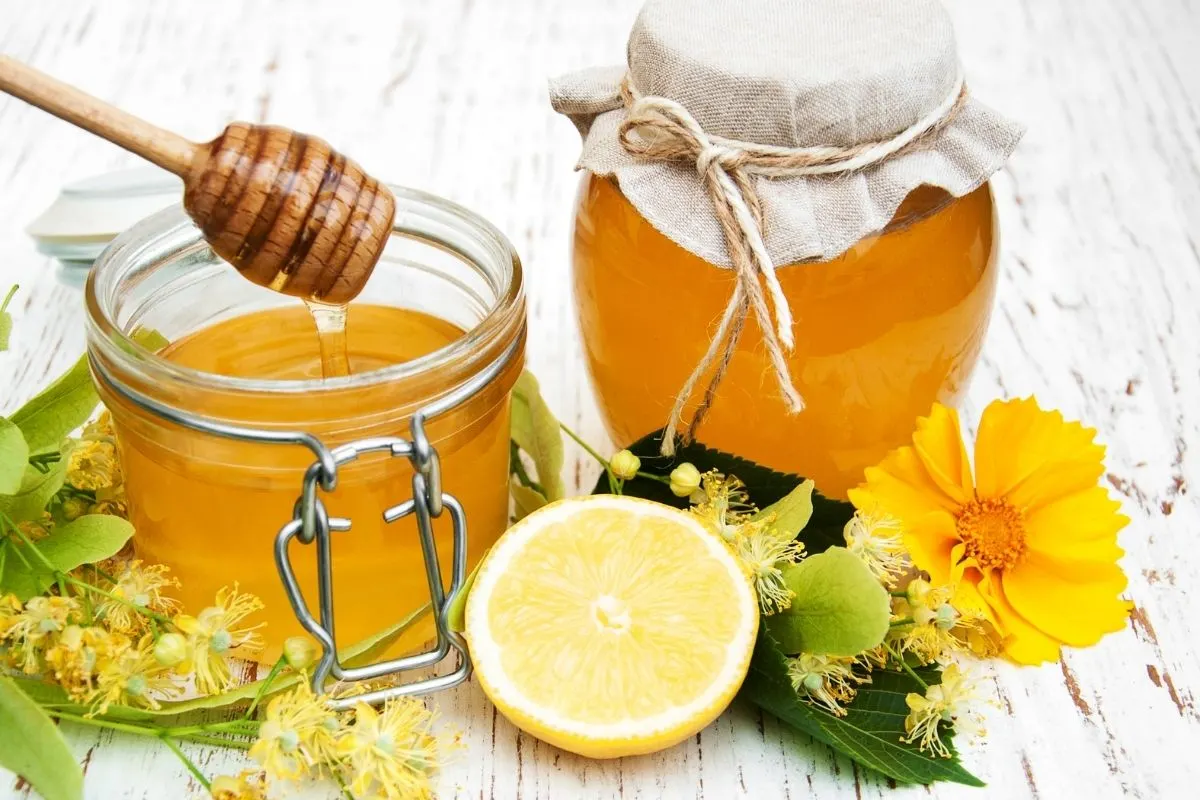 a couple of jars of honey, linden flowers and a cut lemon