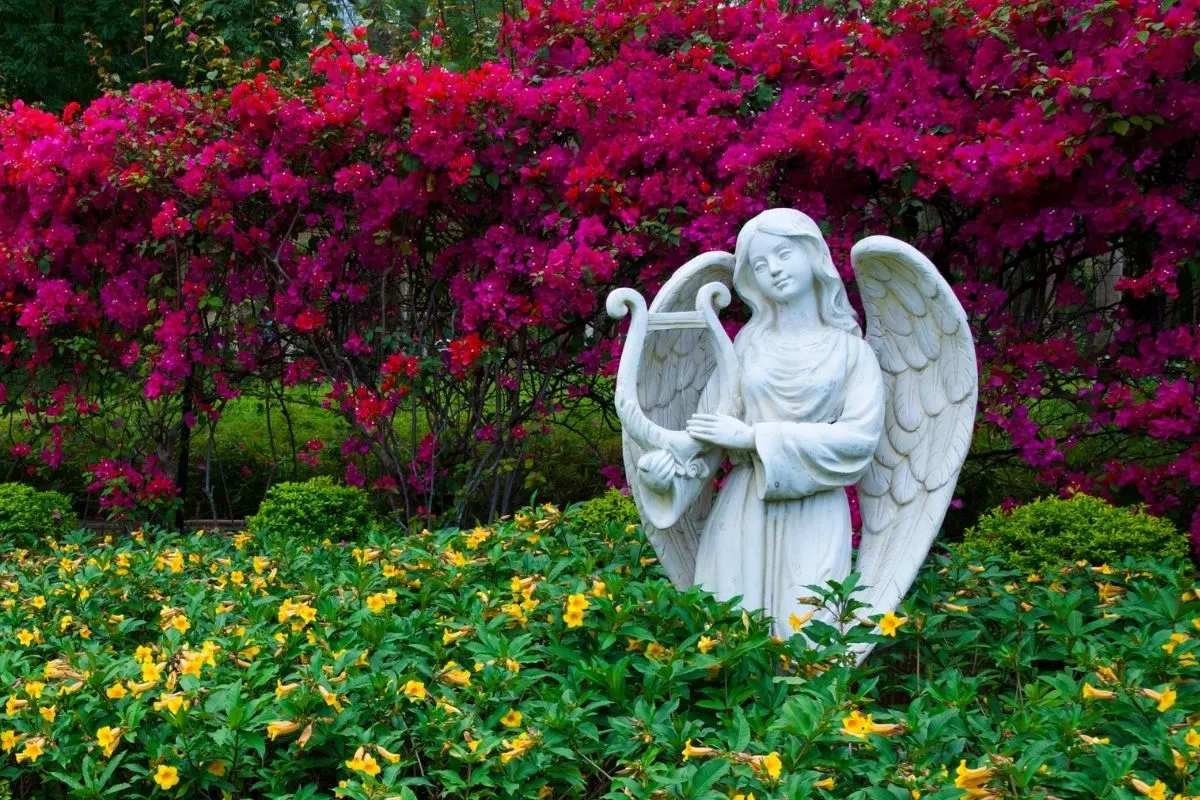 angel garden statue surrounded by red and yellow flowers
