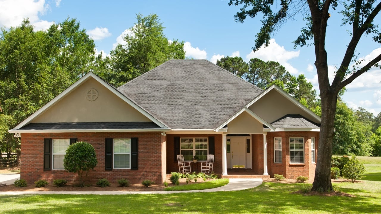 Colonial brick house with beautifully landscaped front yard and mature oak trees
