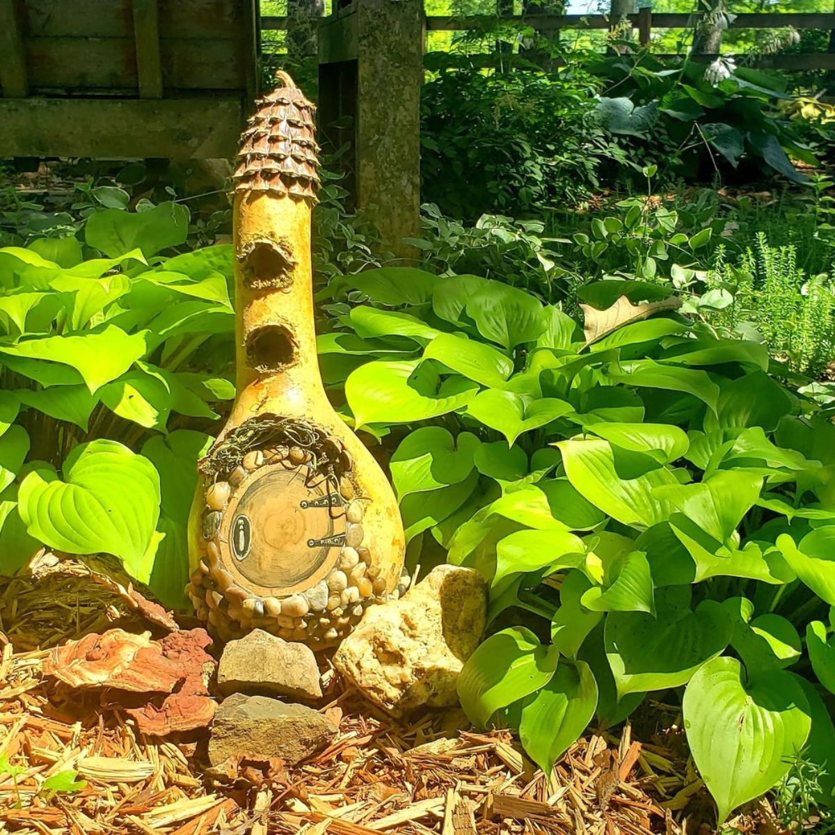 fairy house nestled in front of a hosta plant