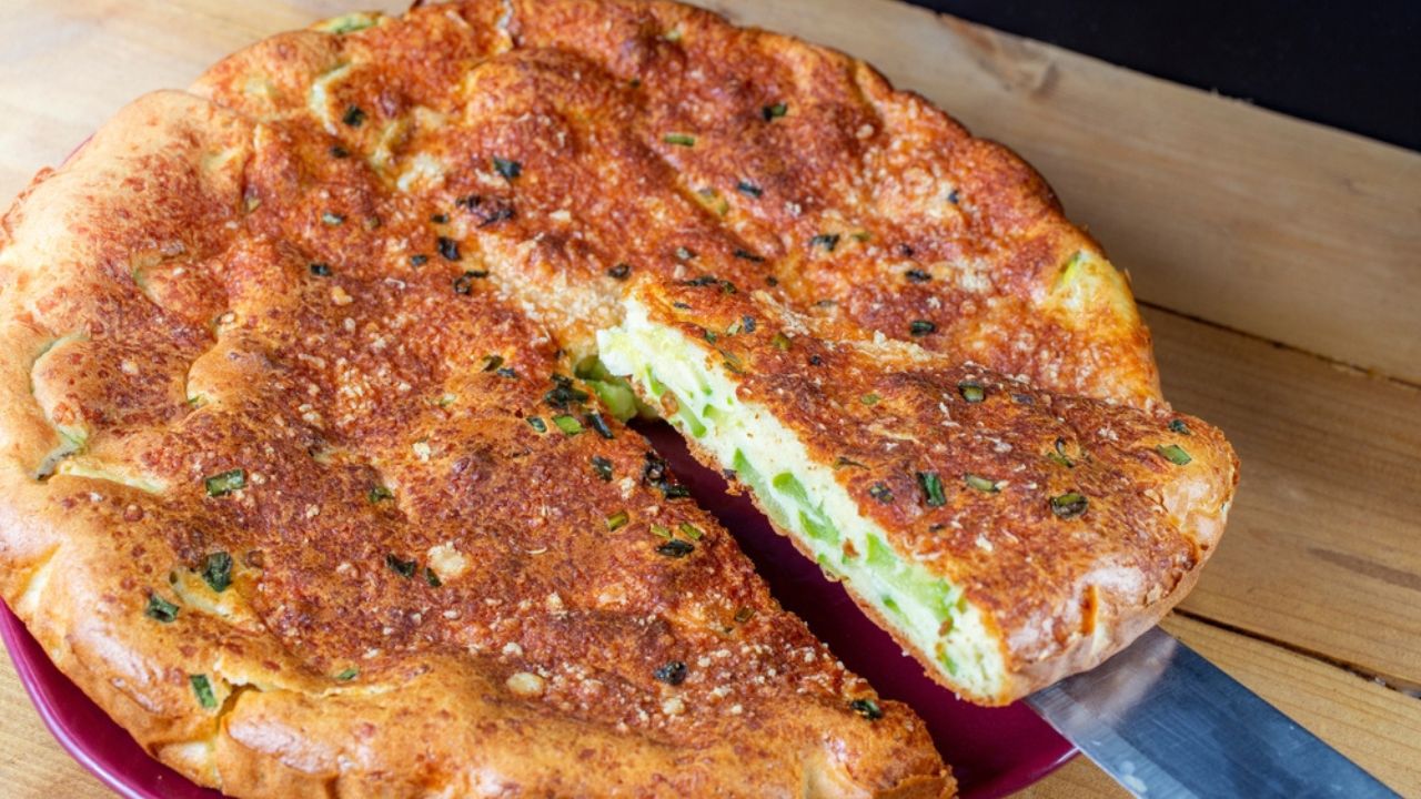 Round Zucchini tart being cut, Knife holding a triangle portion