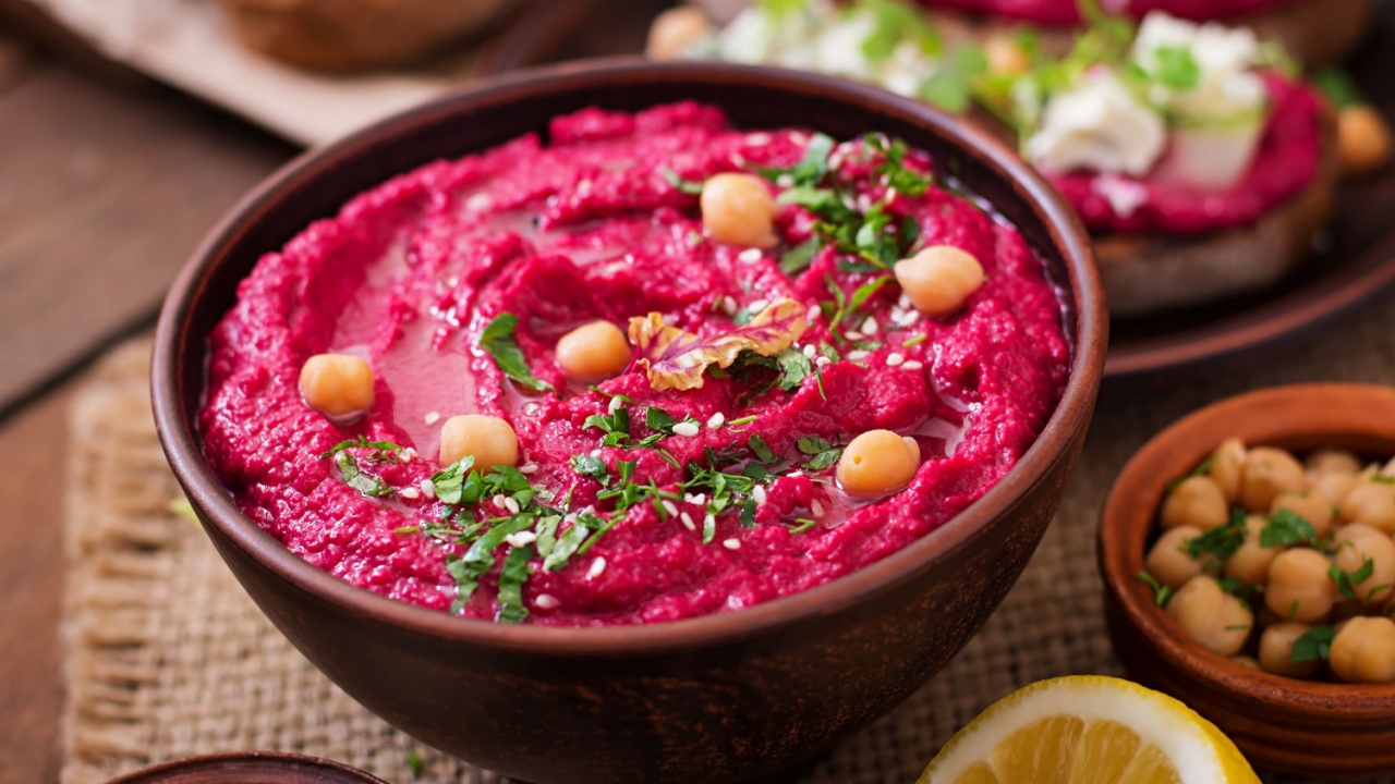 Roasted Beet Hummus with toast in a ceramic bowl on a wooden background