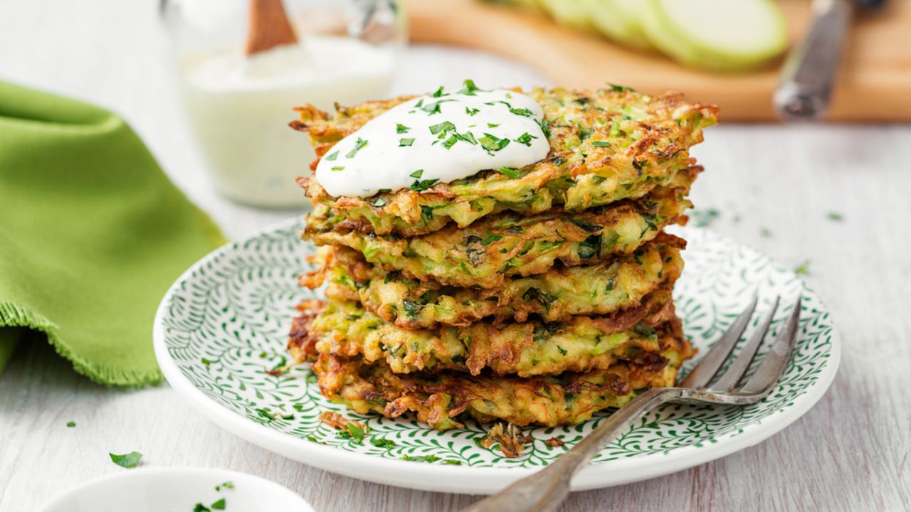 Zucchini fritters, vegetarian zucchini pancakes, served with fresh herbs and sour cream.