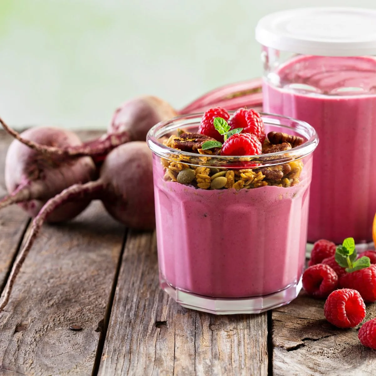 a glass of beet smoothie with whole beets behind the glass