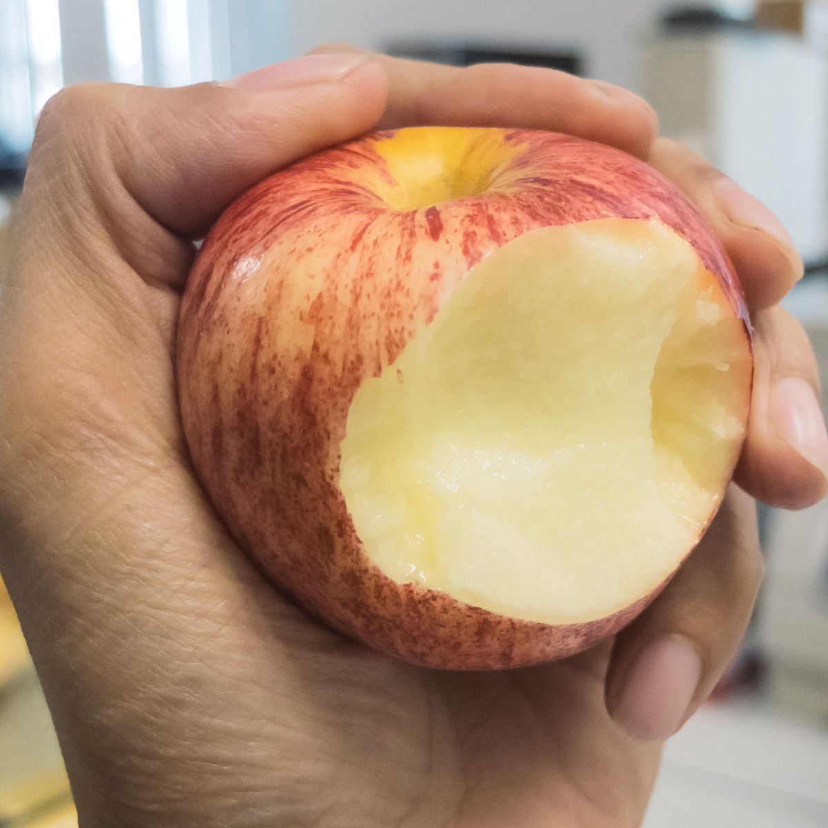 hand holding an apple that was bit into