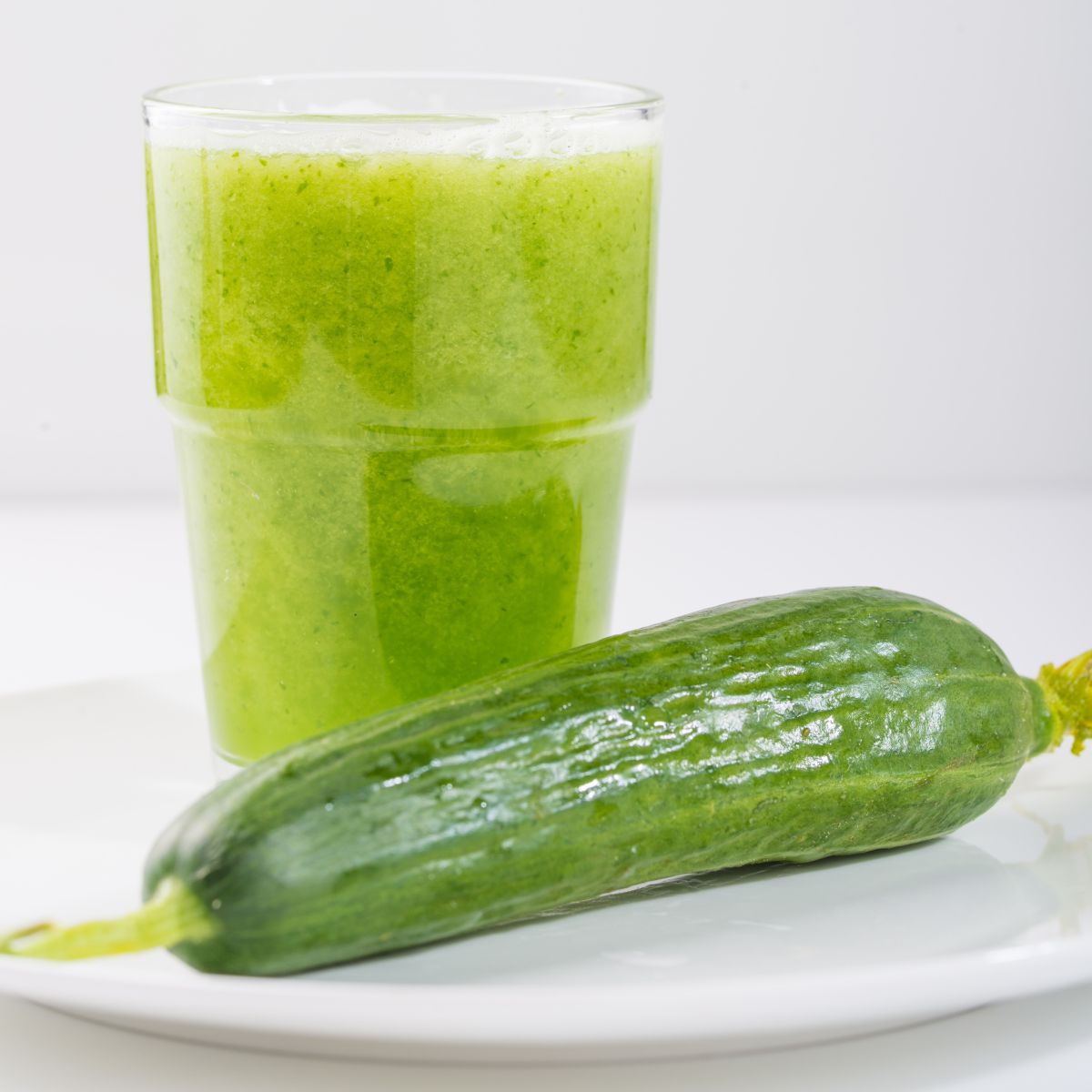 a cucumber next to a glass of cucumber juice