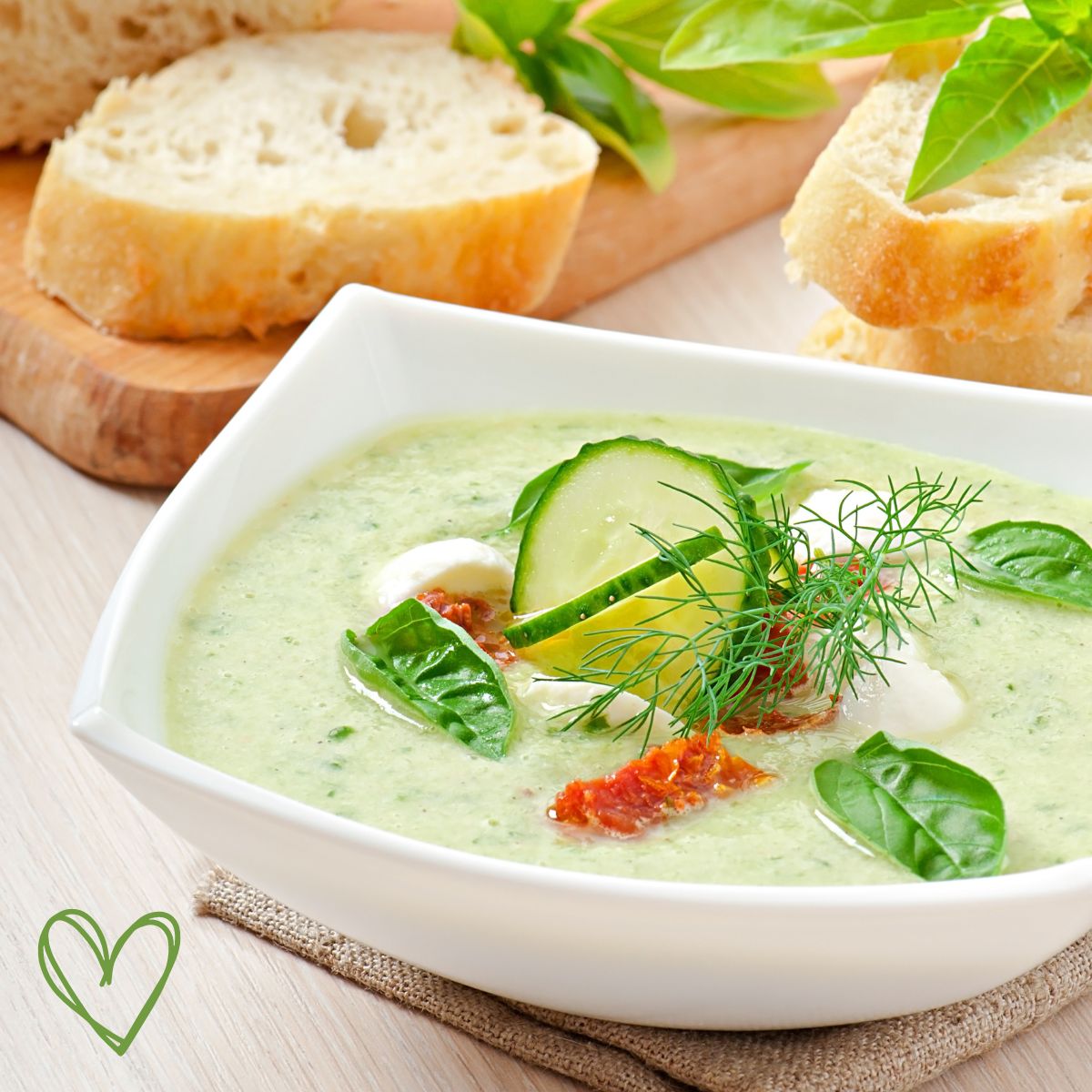 a white bowl with cucumber soup and bread