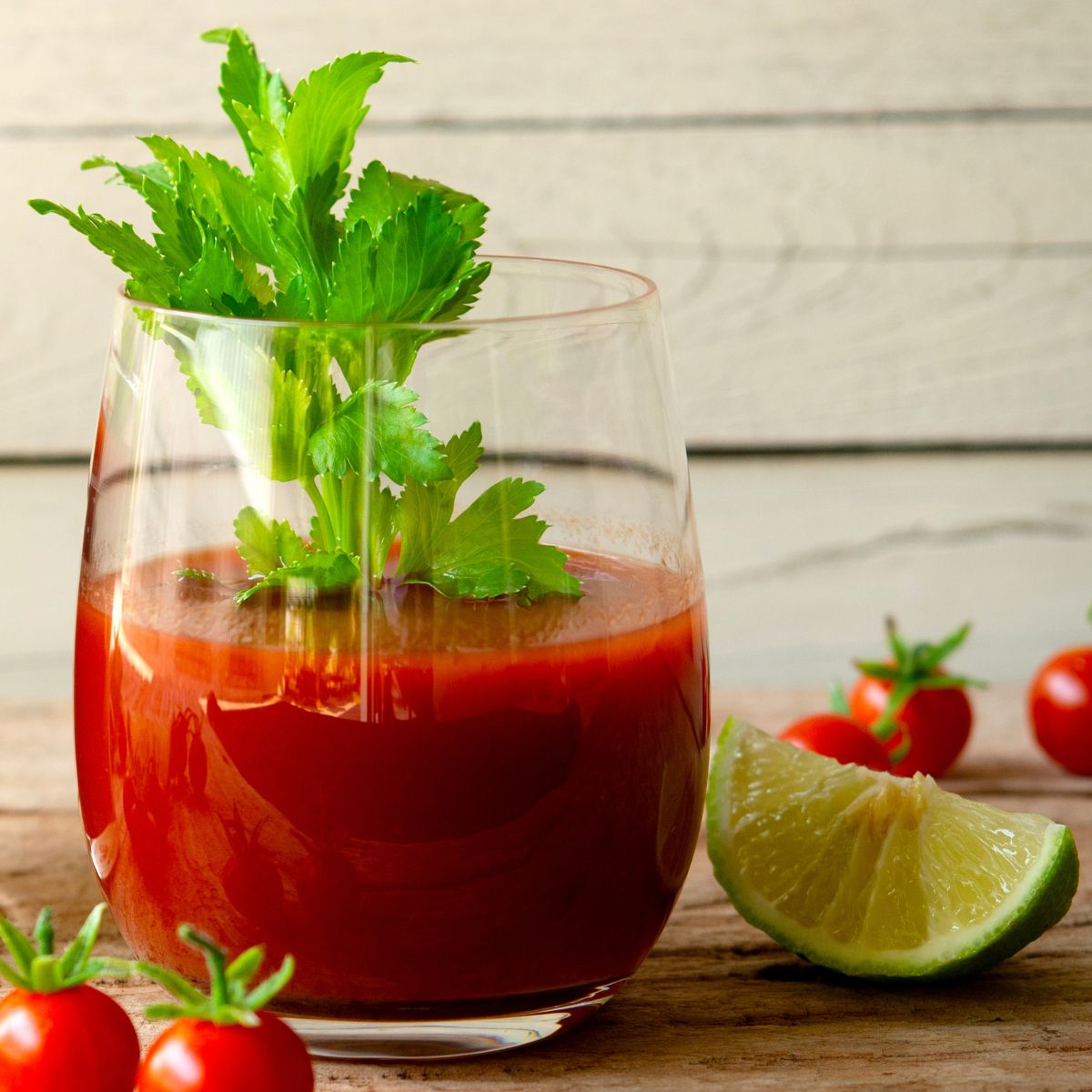 a glass of tomato juice with celery leaves