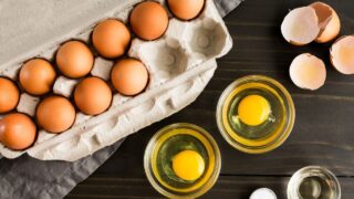 Cracked Eggs in Small Glass Bowls Dishes with cracked eggs next to a paper egg carton and broken brown egg shells