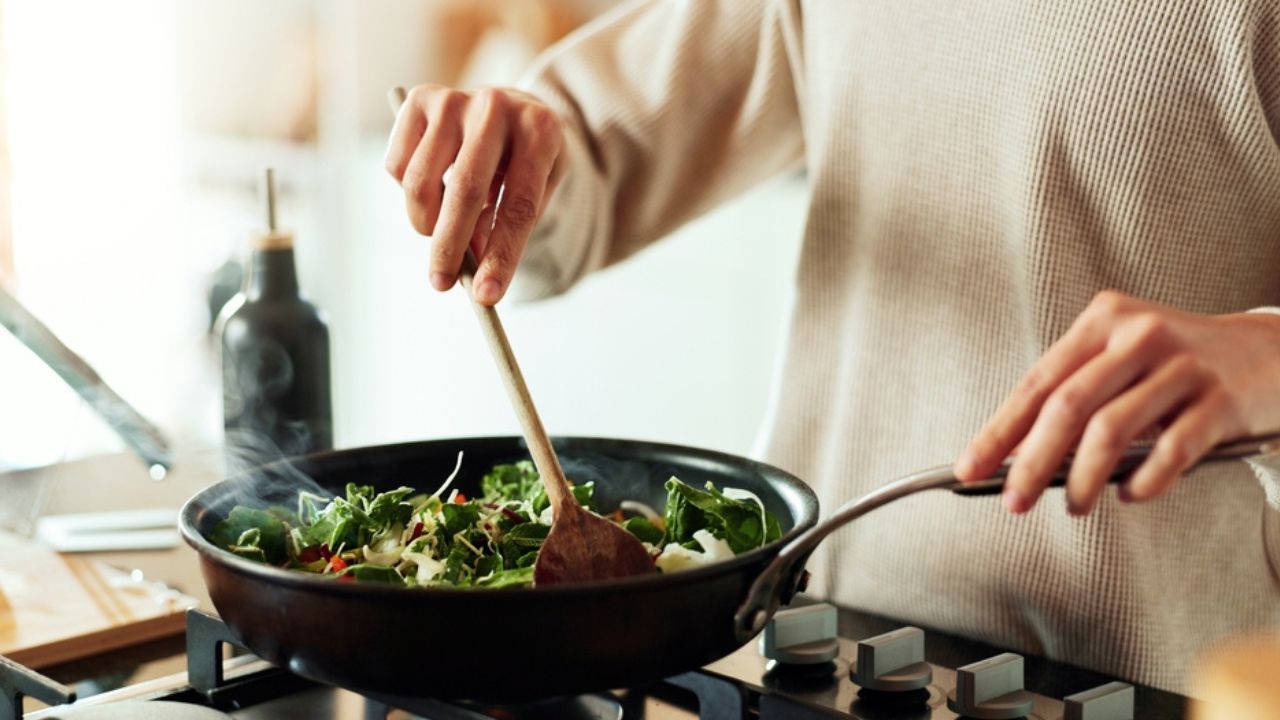Spoon, cooking and hands of woman in kitchen with food, health and wellness with traditional recipe for lunch