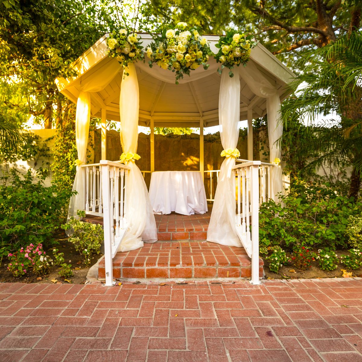 A small white gazebo decorated for a wedding celebration. 