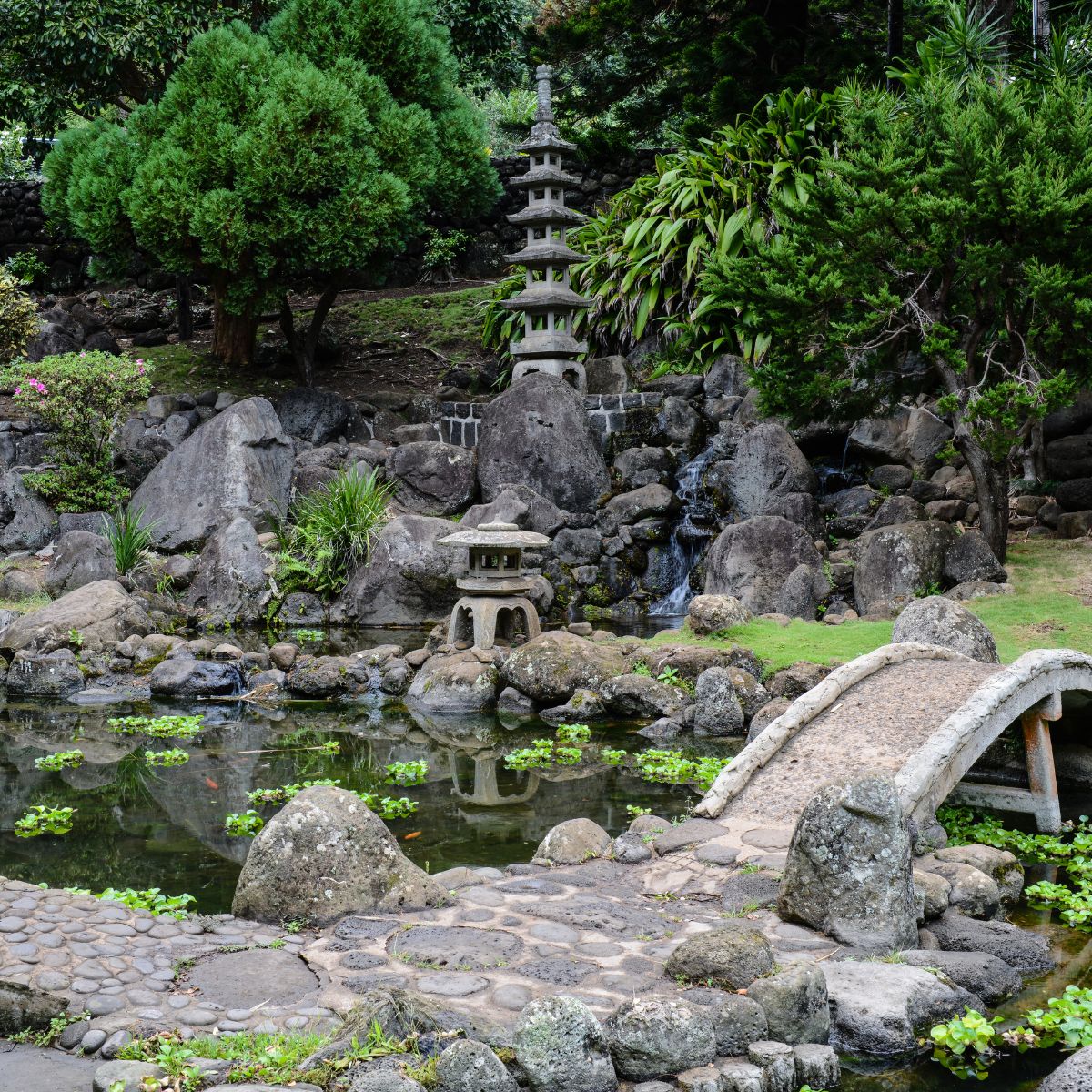 Asian style garden with lots of rocks, a pond and a stone bridge.  